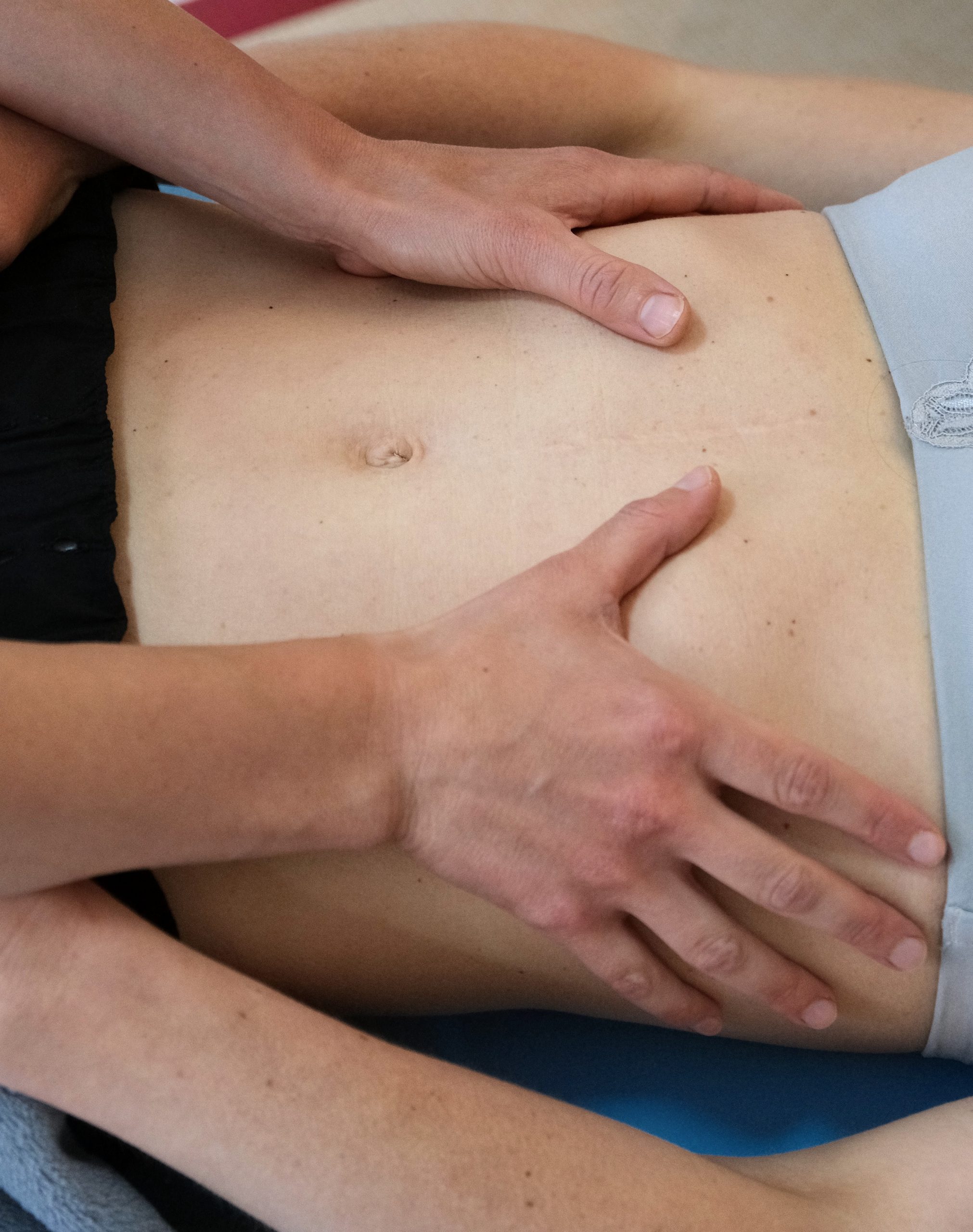 Liegende Patientin, Hände der Therapeutin auf dem Bauch.