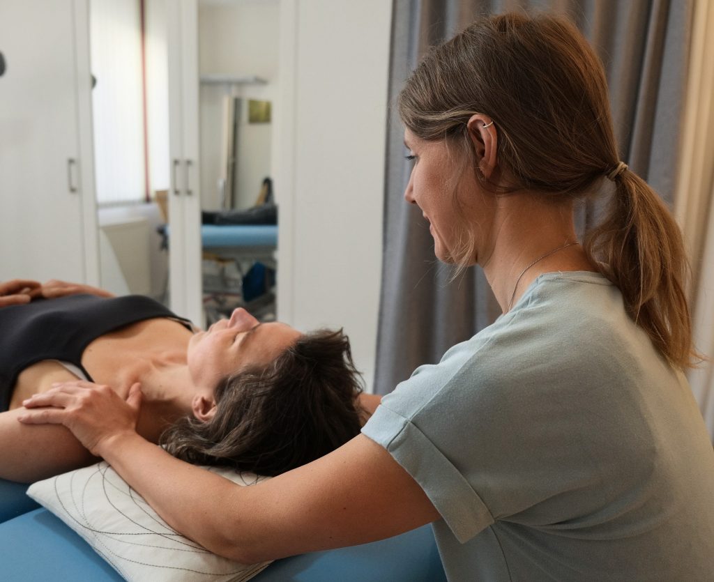 Liegende Patientin, Hände der Therapeutin auf den Schultern.